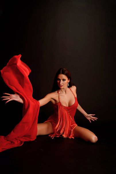 sexy brunette in a red suit on a dark background in the studio - Photo, image