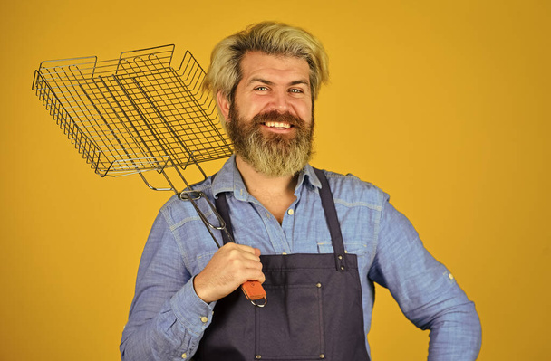 Tools for roasting meat. Cooking utensils. Chef cooking bbq food. Summer picnic. Hipster dyed beard promoting bbq equipment. Cooking healthy. Man in apron hold barbecue grill. Culinary concept - Foto, Imagen