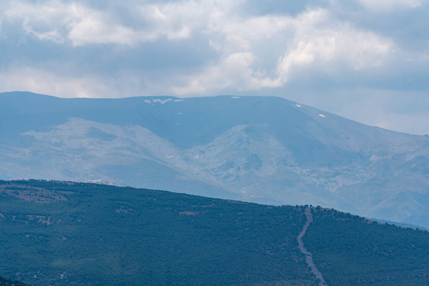 Гірський краєвид в Сьєрра-Неваді на півдні Іспанії, тут є соснові ліси, трава, на небі хмари. - Фото, зображення