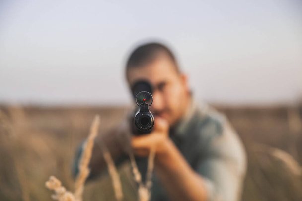 Hunter apunta en el campo con un rifle de francotirador. enfoque en hocico - Foto, imagen