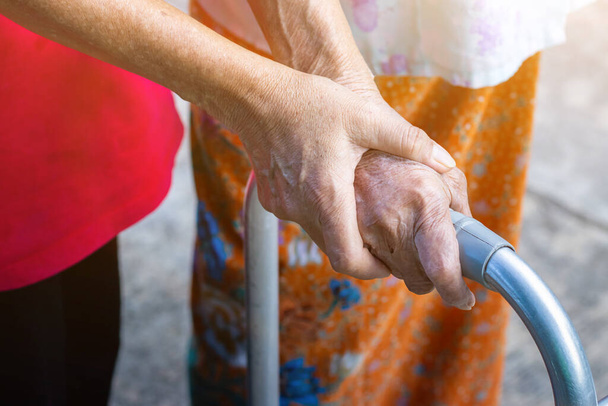 Asian old woman standing with her hands on a walker with daughter's hand,Hand of old woman holding a staff cane for helping walkin - Foto, Bild