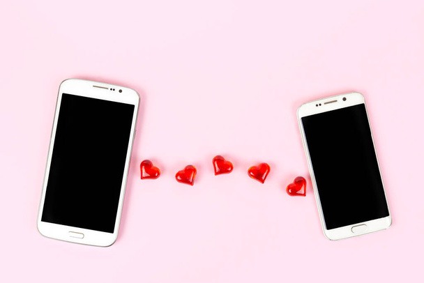 Mobilní telefon s černou obrazovkou a červené srdce izolované na růžovém pastelovém pozadí. Horní pohled, plochá poloha, kopírovací prostor. Valentines day, love, technology, online dating concept. - Fotografie, Obrázek
