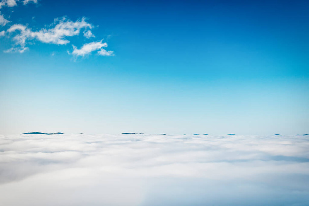 Top peaks of mountains in white clouds and blue sky - Photo, Image