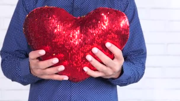 χέρι κρατώντας κόκκινο σύμβολο της καρδιάς κοντά  - Πλάνα, βίντεο