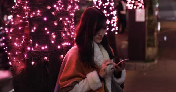 Japonská dívka posílá zprávu v noci osvětlené ulici v Shibuya close shot - Záběry, video