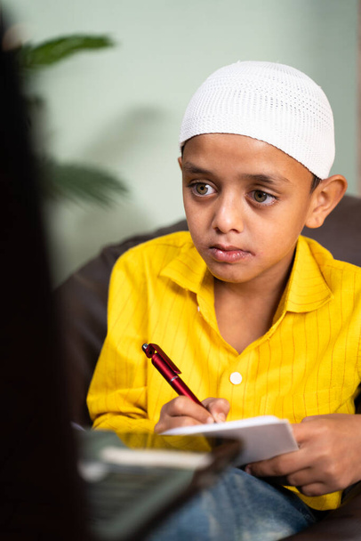 Мусульманські діти пишуть нотатки під час онлайн-занять у відео-дзвінках на ноутбуці - концепція електронного навчання, віртуальної освіти та домашньої освіти завдяки коронавірусу або пандемії коїд-19. - Фото, зображення