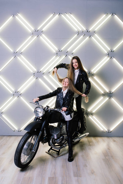 Due belle ragazze che indossano costumi di corridori e seduti su una moto in studio - Foto, immagini