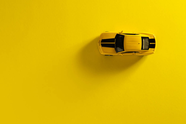 Izmir, Turkey - September 30, 2020: Top view of a Yellow toy car on a Yellow background with long and side shadow. - Foto, Bild