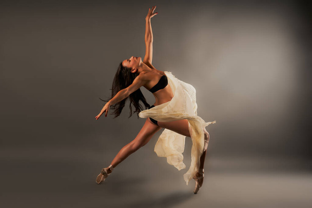 Ballet danser met zwart lingerie en gaas bedekken haar doen dans pose - Foto, afbeelding