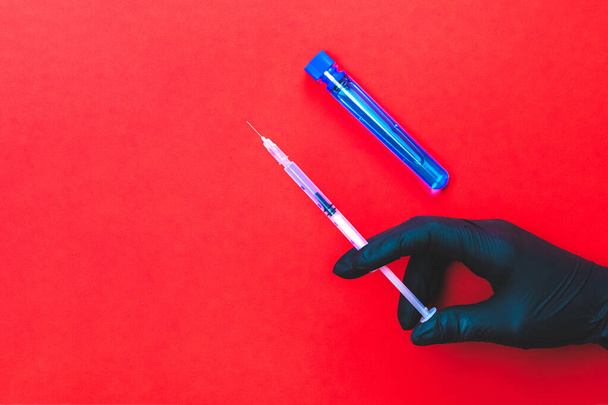 Szczepionka odizolowana. Ręka lekarza w rękawiczce trzymać strzykawkę z igłą do ochrony wirusa grypy i koronawirusa. Szczepionka Covid wyizolowana na czerwono. Sprzęt do szczepień z tworzywa sztucznego z igłą - Zdjęcie, obraz