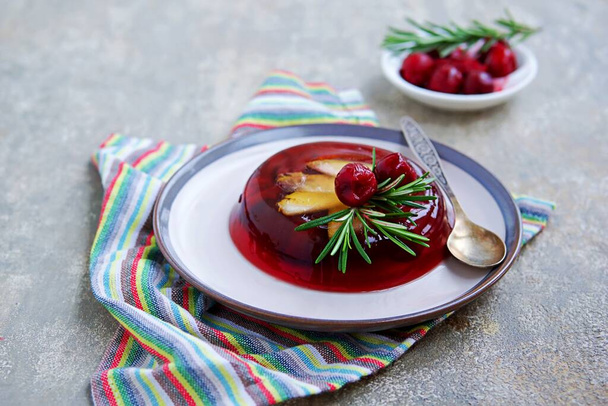 Dessert, cherry jelly with pear on a ceramic plate on a gray concrete background. Jelly recipes. Lenten recipes. - Фото, изображение