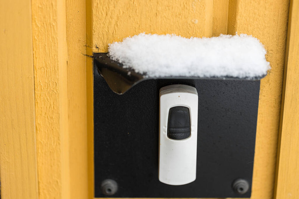 Vista cercana de la cubierta protegida con nieve sobre el botón del timbre eléctrico. Concepto temporada invierno. - Foto, imagen