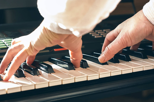 Músico femenino tocando el piano digital o el teclado electrónico en casa. Educación musical y entretenimiento. Clases de música en línea.Foco selectivo - Foto, imagen