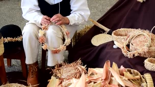 Ремесленница, делающая корзинки, короны и повязки из кукурузной шелухи на ярмарке в Галисии, Испания - Кадры, видео