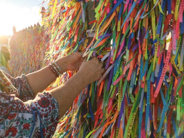 Manos femeninas atando cintas de colores en la rejilla de la iglesia Bonfim en Salvador Bahia Brasil. - Foto, Imagen