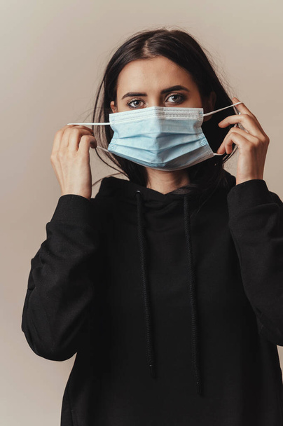 Medical face mask for protection from viruses, used by brunette female  - Foto, Bild