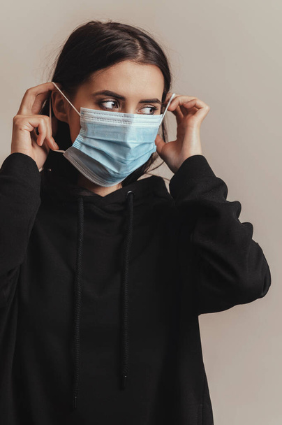Medical face mask for protection from viruses, used by brunette female  - Fotografie, Obrázek