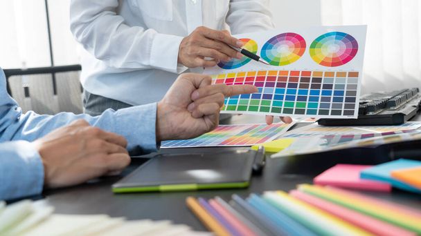 Γραφίστας ή δημιουργικός που εργάζονται μαζί χρωματισμός χρησιμοποιώντας tablet γραφικών και μια γραφίδα στο γραφείο με συνάδελφο - Φωτογραφία, εικόνα
