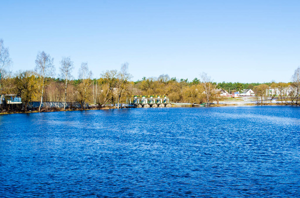 landscape of blue lake near forest and village - Zdjęcie, obraz