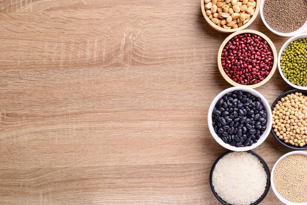 Various cereal grain in a bowl on wooden background (quinoa seeds, black kidney bean, peanut, perilla seeds, soybean, azuki beans, rice grain and mung beans) - Fotoğraf, Görsel