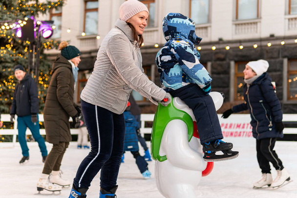 Kijów (Kijów), Ukraina - 27 grudnia 2020: Wielu szczęśliwych ludzi i dzieci jeździ na łyżwach na zewnątrz w pobliżu Urzędu (Administracji) Prezydenta Ukrainy - Zdjęcie, obraz