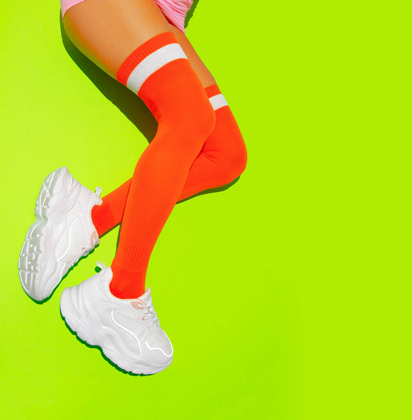 Stylové bílé tenisky a oranžové punčochy na žlutém čerstvým minimálním pozadí. Sport fitness letní aktivní vibrace - Fotografie, Obrázek