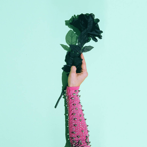 Hand with thorns holding a black rose. Minimal creative concept - Zdjęcie, obraz