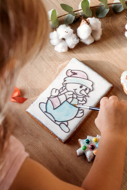 Little girl decorates New Year's gingerbread. Gingerbread snowman. - Foto, Imagem