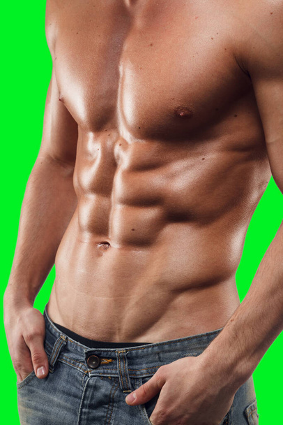 Close up of naked torso of strong man in jeans, posing in studio green screen chrome key background. - Photo, Image