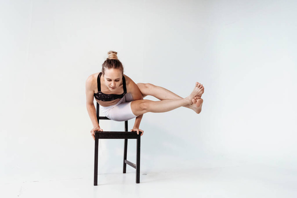 Ragazza di yoga su una sedia facendo stretching su sfondo bianco. - Foto, immagini