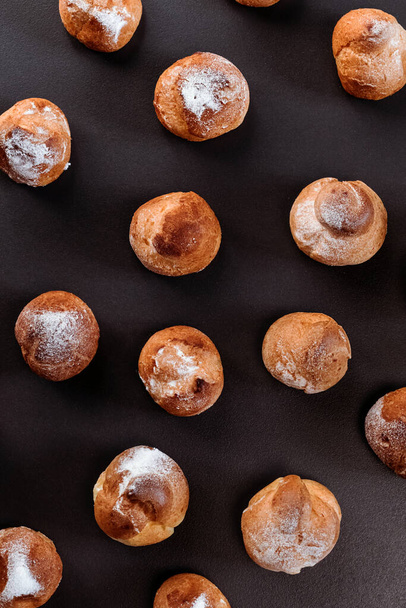 French profiteroles with cream. View from above. Many sweets on dark background. - Photo, Image