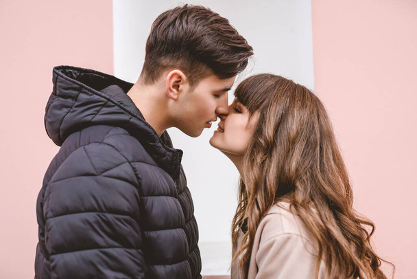 Bir adam ve bir kadın pembe duvarda öpüşüyorlar. - Fotoğraf, Görsel