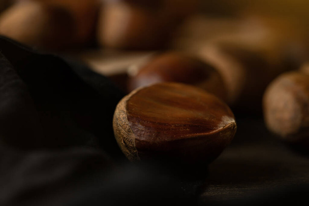 Not roasted fresh chestnuts in a wooden table. Sweet chestnuts. - Photo, Image