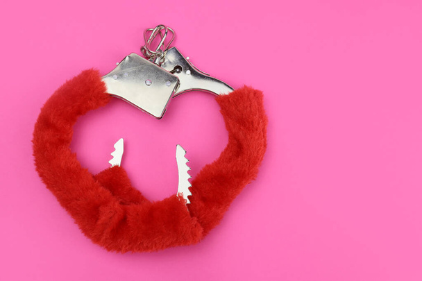 pink fluffy handcuffs in the form of a heart on a pink background. Valentine's Day - Photo, image