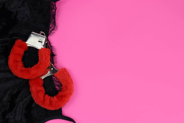 Ροζ χνουδωτές χειροπέδες σε μαύρα δαντελωτά εσώρουχα. Του Αγίου Βαλεντίνου. Χώρος για κείμενο - Φωτογραφία, εικόνα