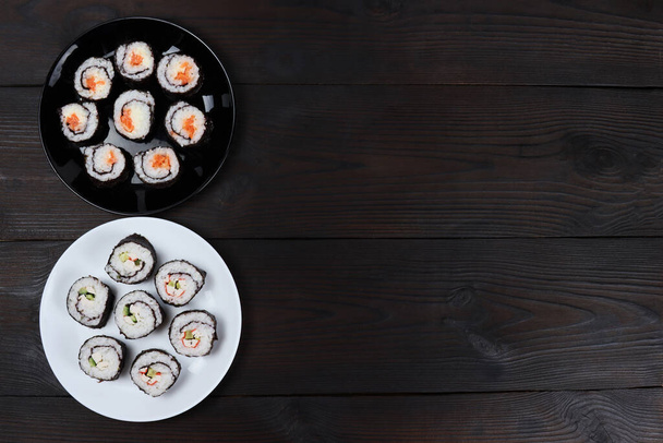 Frescos y deliciosos rollos de sushi en platos sobre una mesa de madera - Foto, Imagen