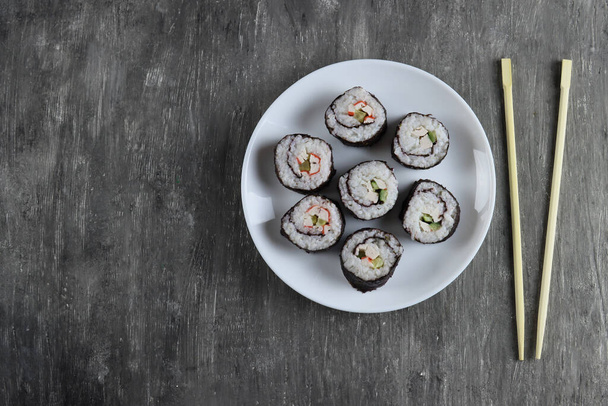 Fresh delicious sushi rolls with cucumber, crab sticks on dark background - Photo, Image