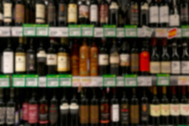Rows of wine bottles on the shelves in the store. Front view. Blurred. - Foto, imagen