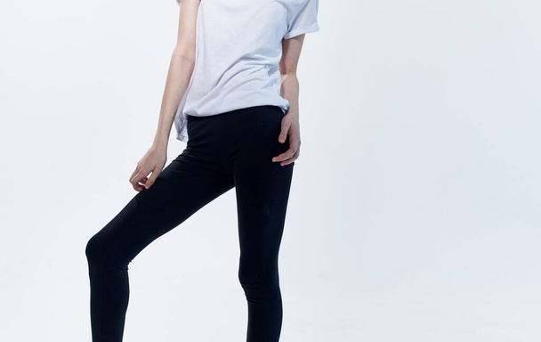 Nő beltéri világos háttér és fekete leggings fehér pólóban - Fotó, kép