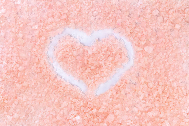 Beige rosa Hintergrund mit weißem Herz. Meersalz. Valentinstag. Textur - Foto, Bild