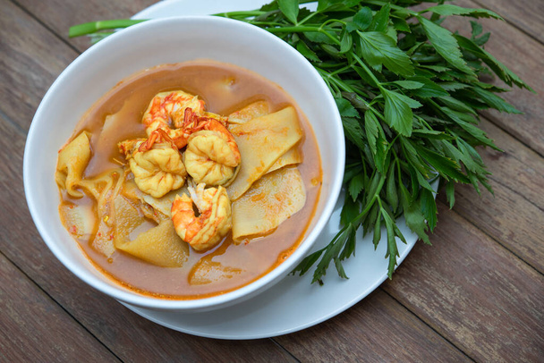 Southern Thai Spicy Sour Yellow Curry con gamberetti o gamberetti e germogli di bambù conservati (Gaaeng Leuuang) mangiati con verdure Water Dropworts o Oenanthe in vendita al ristorante tailandese - Foto, immagini
