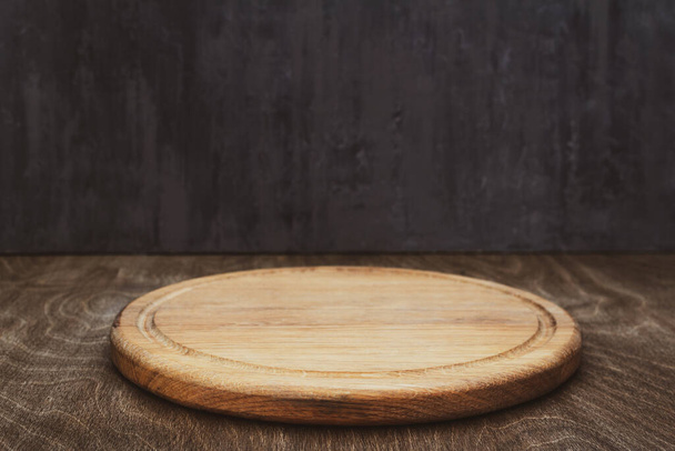 pizza cutting board at wooden table, with wall background texture - Foto, imagen