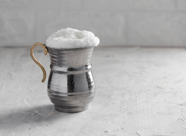 AYRAN. Tradizionale bevanda allo yogurt turco con schiuma in tazza di metallo argentato. Latticello. - Foto, immagini