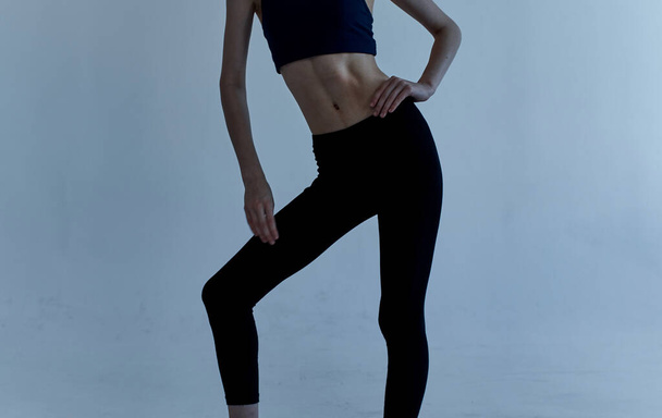Спортивная женщина в леггинсах и футболке занимается фитнесом на светлом фоне - Фото, изображение