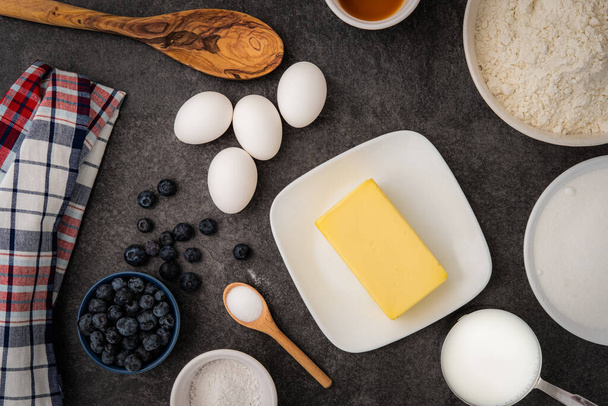 Μια επίδειξη τόσο των υγρών όσο και των ξηρών συστατικών που απαιτούνται για την παρασκευή muffins βατόμουρο στον πάγκο της κουζίνας - Φωτογραφία, εικόνα
