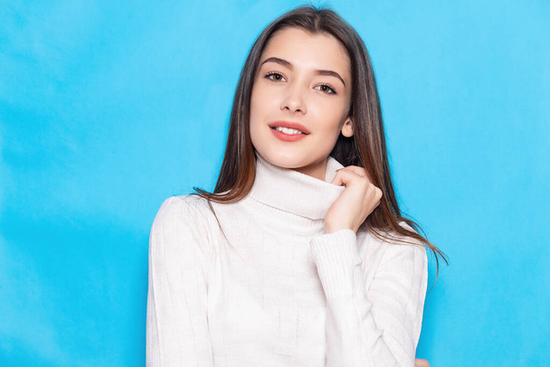 Smiling young brunette woman girl in casual white clothes, posing isolated on pastel blue background studio portrait. People emotions lifestyle concept. Mock up copy space. Looking camera - Foto, afbeelding