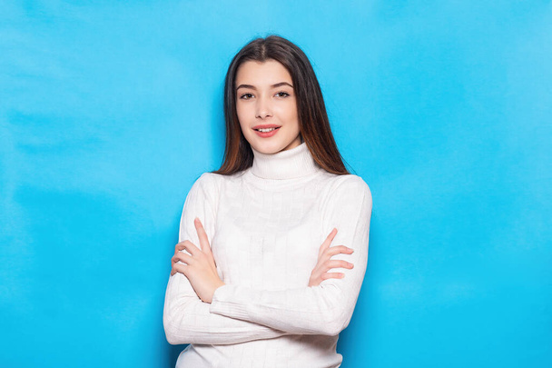 Smiling young brunette woman girl in casual white clothes, posing isolated on pastel blue background studio portrait. People emotions lifestyle concept. Mock up copy space. Looking camera - Фото, изображение