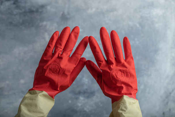 Female hand in red protective gloves on marble background - Photo, Image