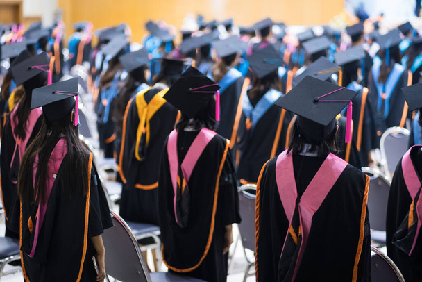 Rearview των αποφοίτων του πανεπιστημίου γραμμή για το βραβείο βαθμό στην τελετή αποφοίτησης πανεπιστήμιο. Οι απόφοιτοι του πανεπιστημίου συγκεντρώνονται στην τελετή αποφοίτησης του πανεπιστημίου. Πλήθος αποφοίτων. - Φωτογραφία, εικόνα