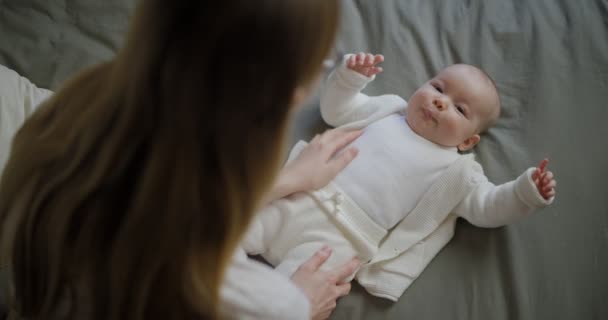 Glückliche Frau schaut ihr Baby an und lächelt. Das schöne Baby lächelt die Mutter an. Mutter mit ihrem eigenen Baby. - Filmmaterial, Video